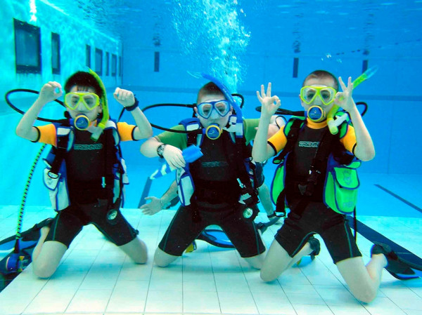 Kids practicing scuba diving routines in a pool