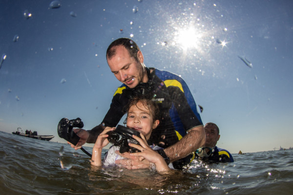 Instructor ayudando a un niño a utilizar el equipo de buceo