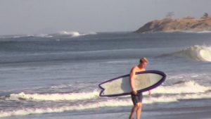 Surfista cargando su tabla en Playa Avellanas