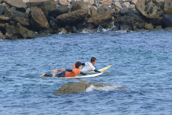 jóvenes practicando a remar sobre las tablas de surf