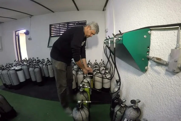 Man refilling diving tank with compressed air