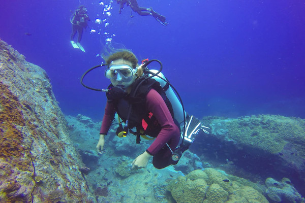 beneficios del buceo-Buzo explorando en las proximidades de una roca debajo del agua
