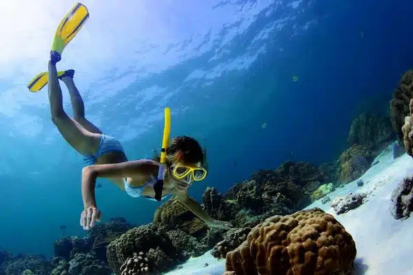 snorkeling vs swimming-Snorkeler observing a rock under water