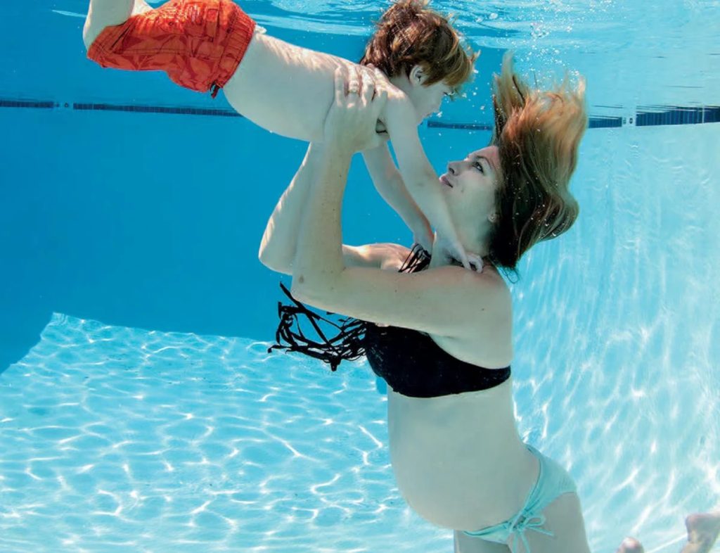 mujer embarazada con su hijo debajo del agua