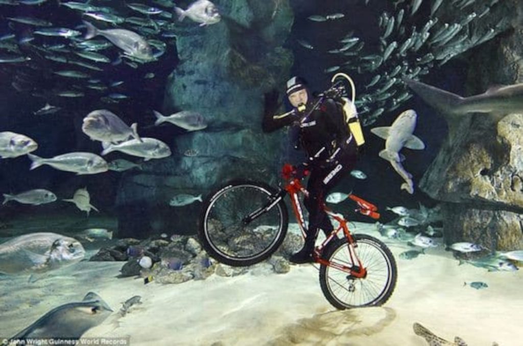 Vittorio Innocente saludando bajo el agua con su bicicleta