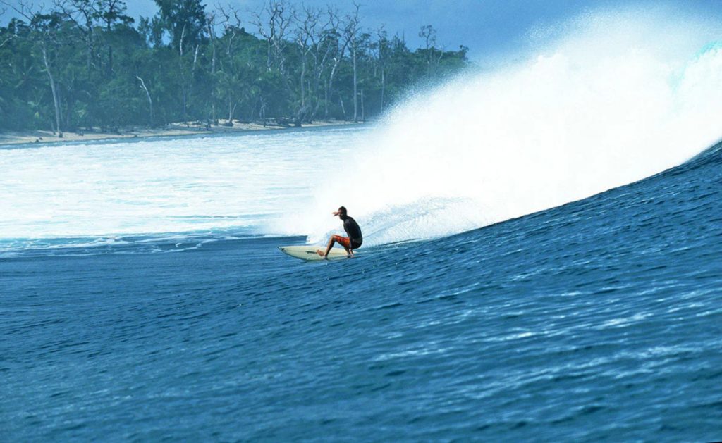Surfista deslizándose sobre las aulas, cerca de la orilla