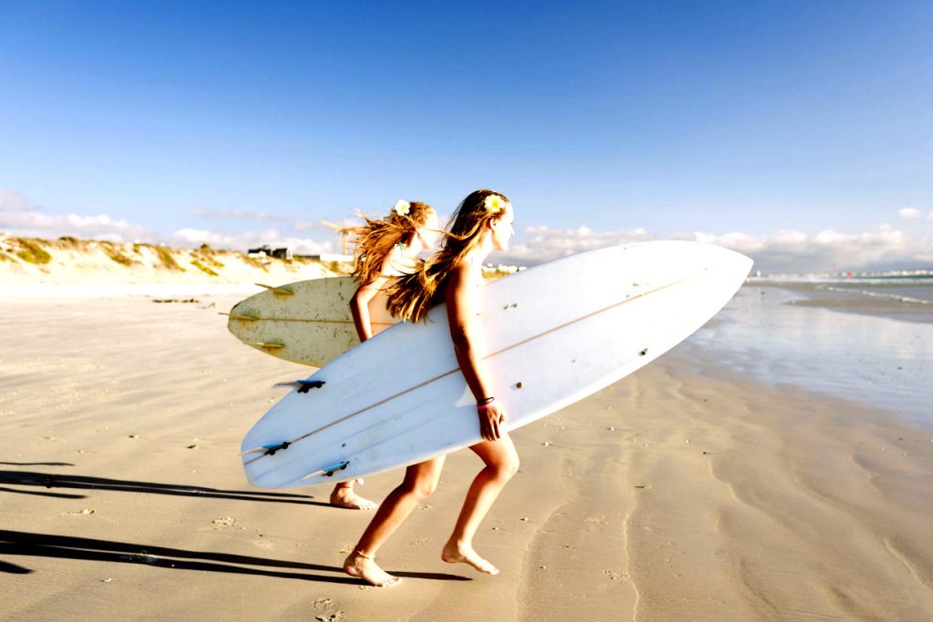 girls talking their surfborad to the sea