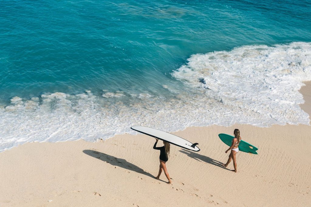 two female surfers entering the water with their surfboards