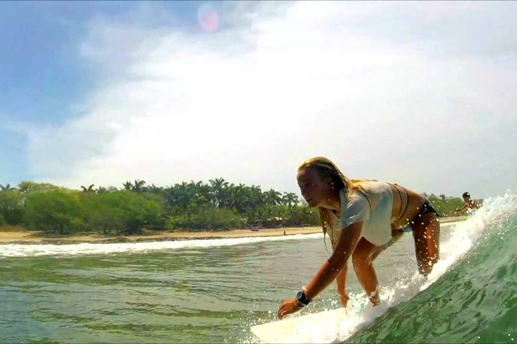 surfista femenina montando su tabla de surf en playa tamarindo Costa Rica