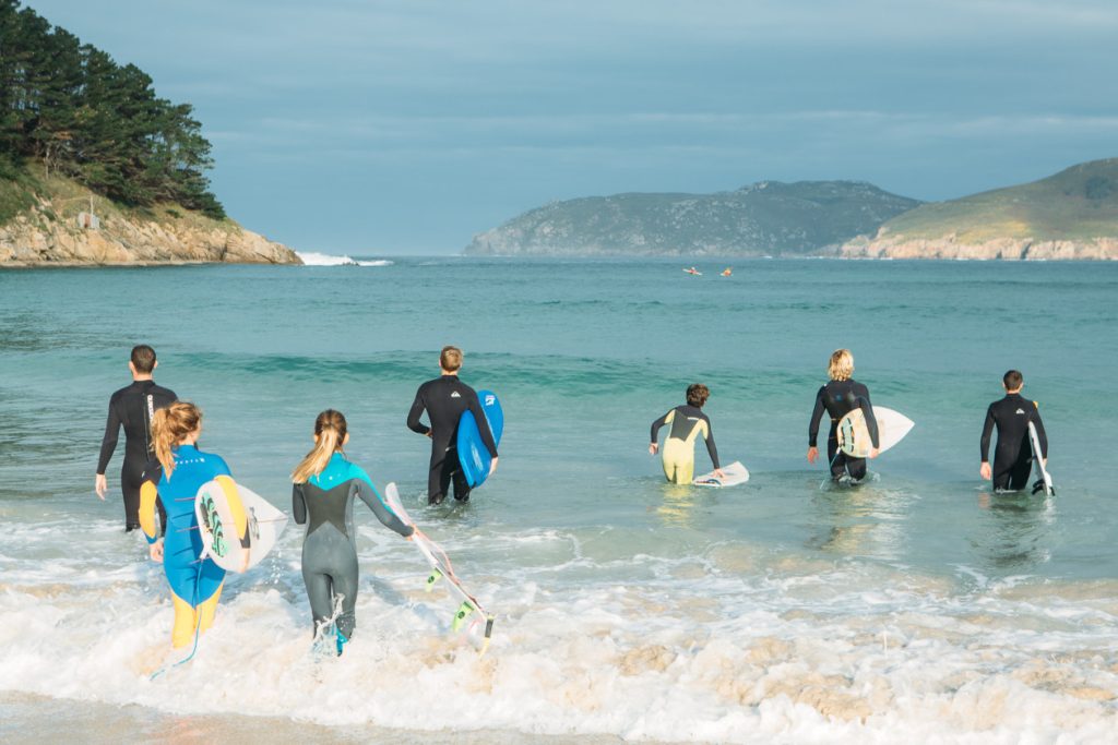 A group of people entering the water with surfboards