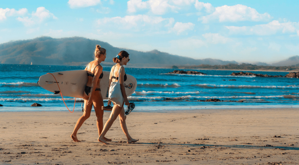 Two people walking on a beach with surfboards