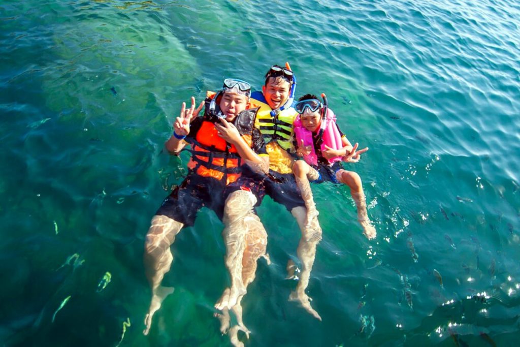 Tres chicos flotando felices en el agua del mar.
