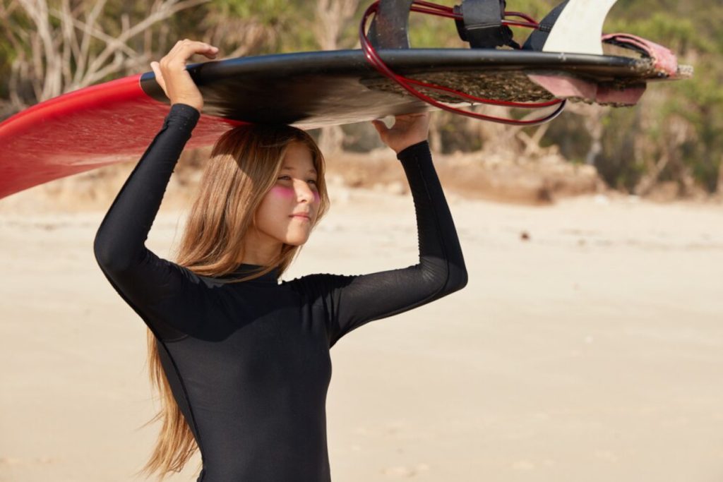 A woman holding a surfboard on her head,