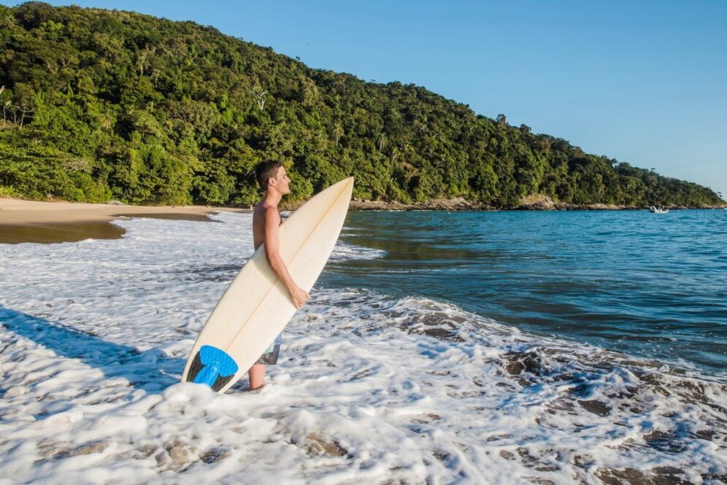un hombre llevando una tabla de surf al océano-