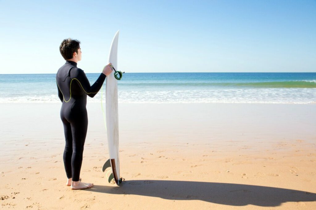 surfista parado en la orilla, preparado para leer las olas