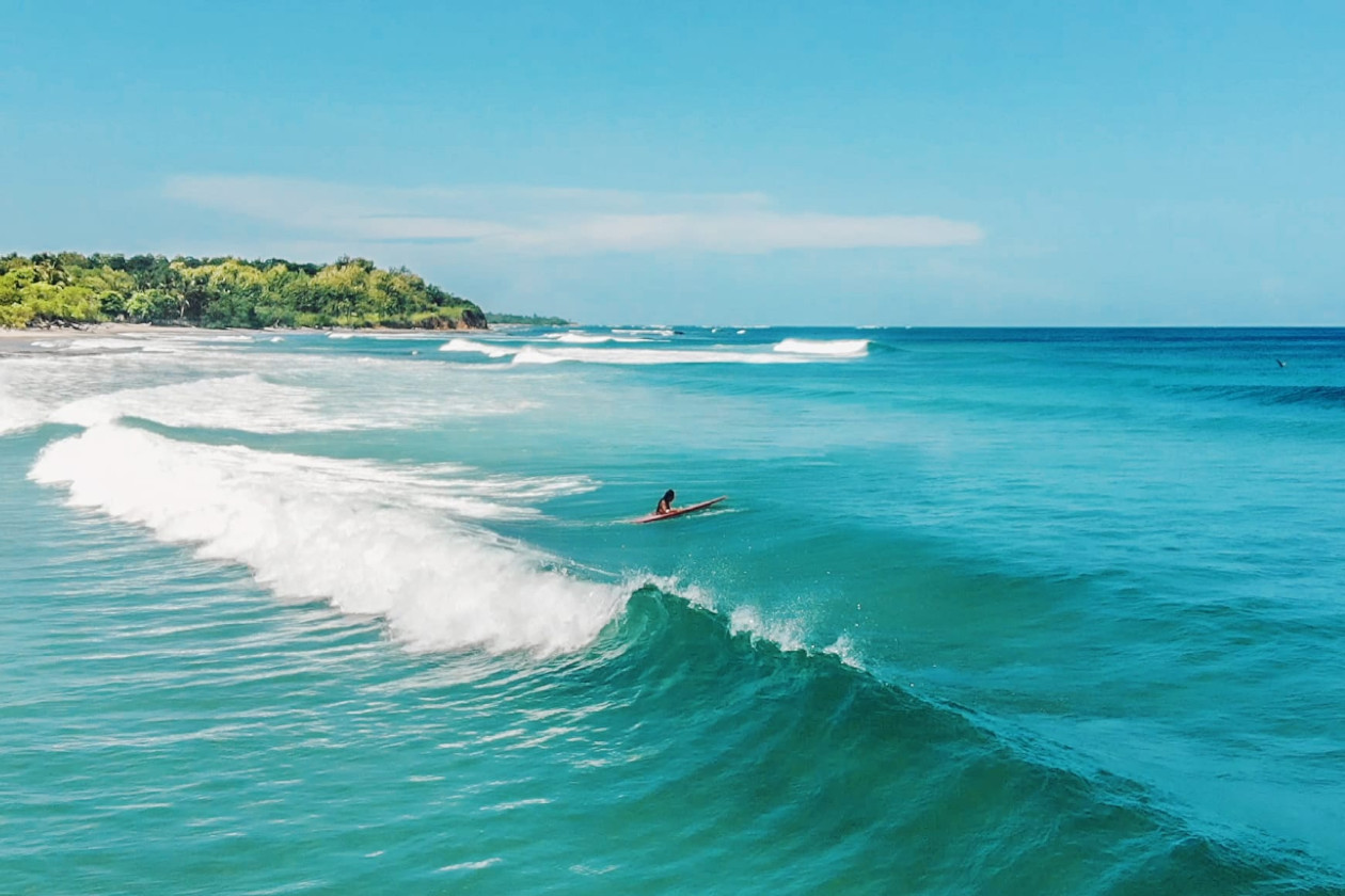 Una persona montando su tabla de surf en playa tamarindo