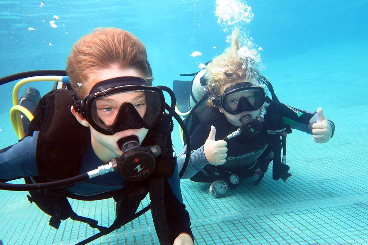 Dos niños practicando buceo seguro en una piscina